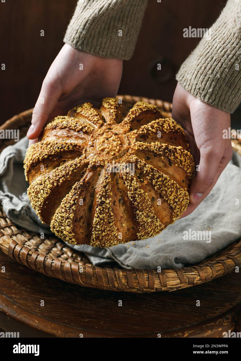 Mains de femmes portant du pain frais fait maison de l'orge et de la farine de maïs. Concept de nourriture saine végétarienne et végétarienne. Style rustique sombre. Banque D'Images