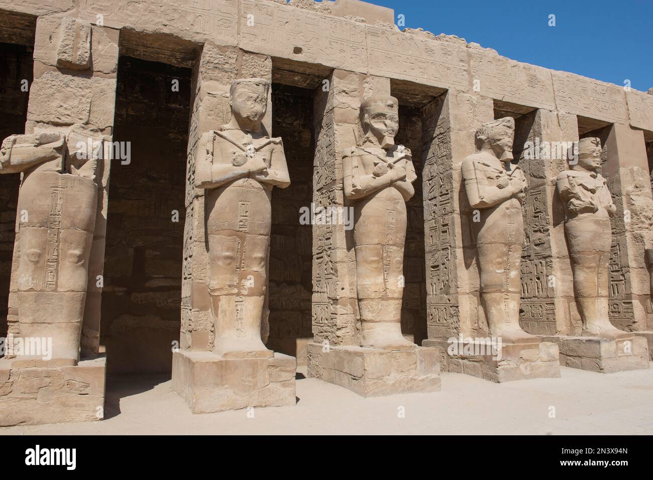 Grandes statues de Ramsès III dans l'ancien temple égyptien de Karnak avec des colonnes dans la cour Banque D'Images