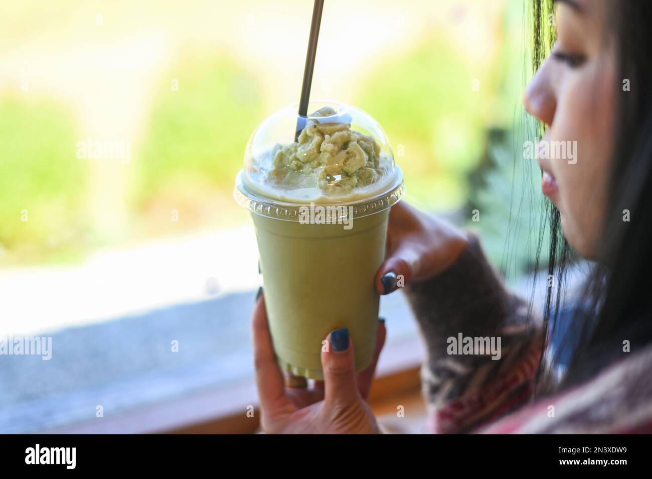 thé vert smoothie plastique tasse femme main tenant une tasse de thé vert dans le café, jeune femme buvant du lait thé femme détendue Banque D'Images
