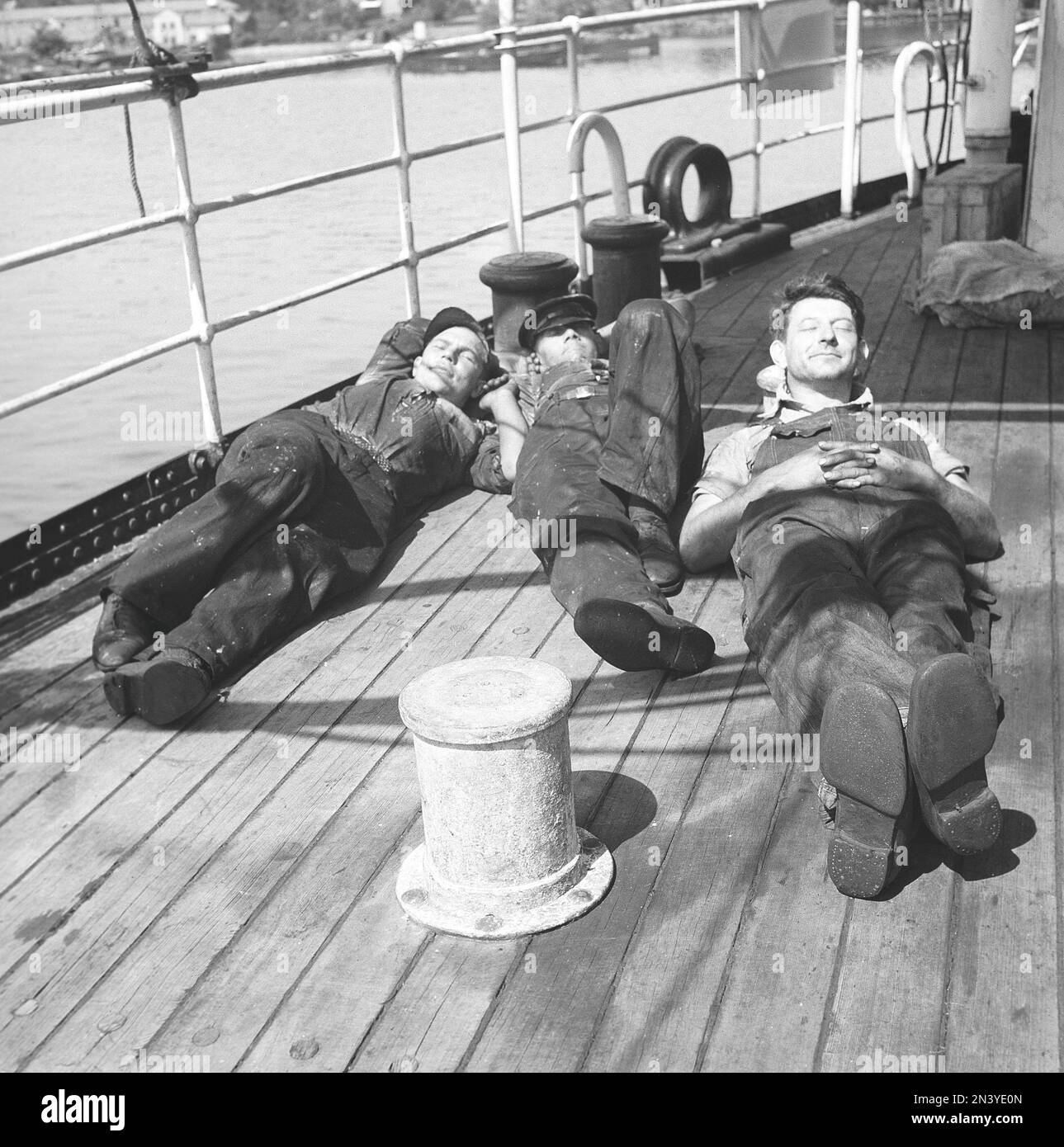 Avoir une sieste dans le 1940s. Trois marins fatigués reposant sur le pont au soleil. Ils font partie de l'équipage d'un navire norvégien, coincé en Suède pendant la Seconde Guerre mondiale, sans avoir la chance de retourner en Norvège qui à cette époque a été envahi par l'Allemagne nazie. Suède 11 juin 1940 Kristoffersson réf. 147-13 Banque D'Images