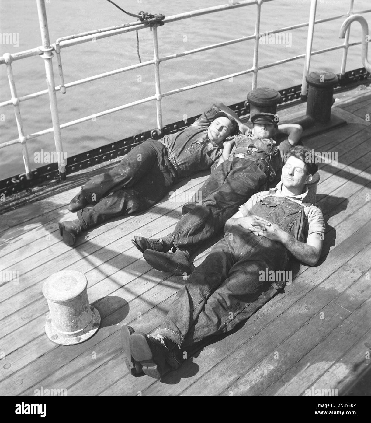 Avoir une sieste dans le 1940s. Trois marins fatigués reposant sur le pont au soleil. Ils font partie de l'équipage d'un navire norvégien, coincé en Suède pendant la Seconde Guerre mondiale, sans avoir la chance de retourner en Norvège qui à cette époque a été envahi par l'Allemagne nazie. Suède 11 juin 1940 Kristoffersson réf. 147-12 Banque D'Images