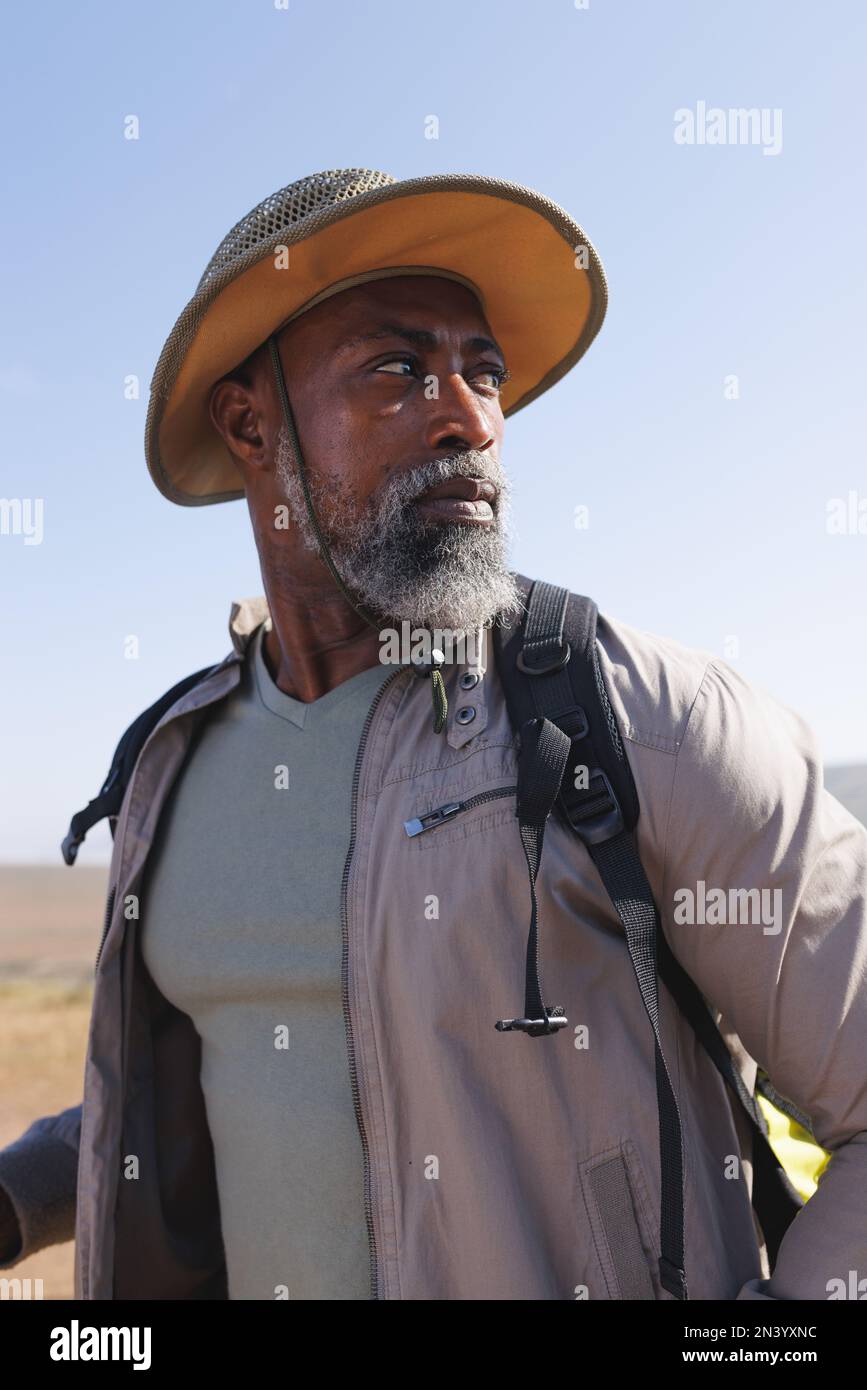 Homme senior afro-américain portant un chapeau et regardant loin tout en se tenant debout contre le ciel dégagé Banque D'Images