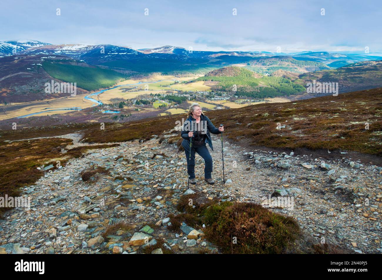 Un marcheur sur le chemin jusqu'à la montagne Corbett de Morrone, ou Morven près de Braemar, Aberdeenshire. Le village de Braemar est vu au loin Banque D'Images
