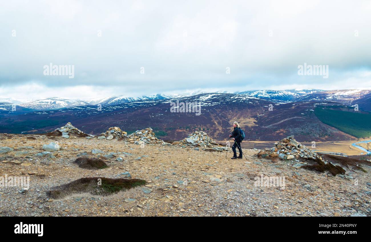 Un marcheur à côté de la 5 cairns sur le chemin jusqu'à la montagne Corbett de Morrone, ou Morven près de Braemar, Aberdeenshire Banque D'Images