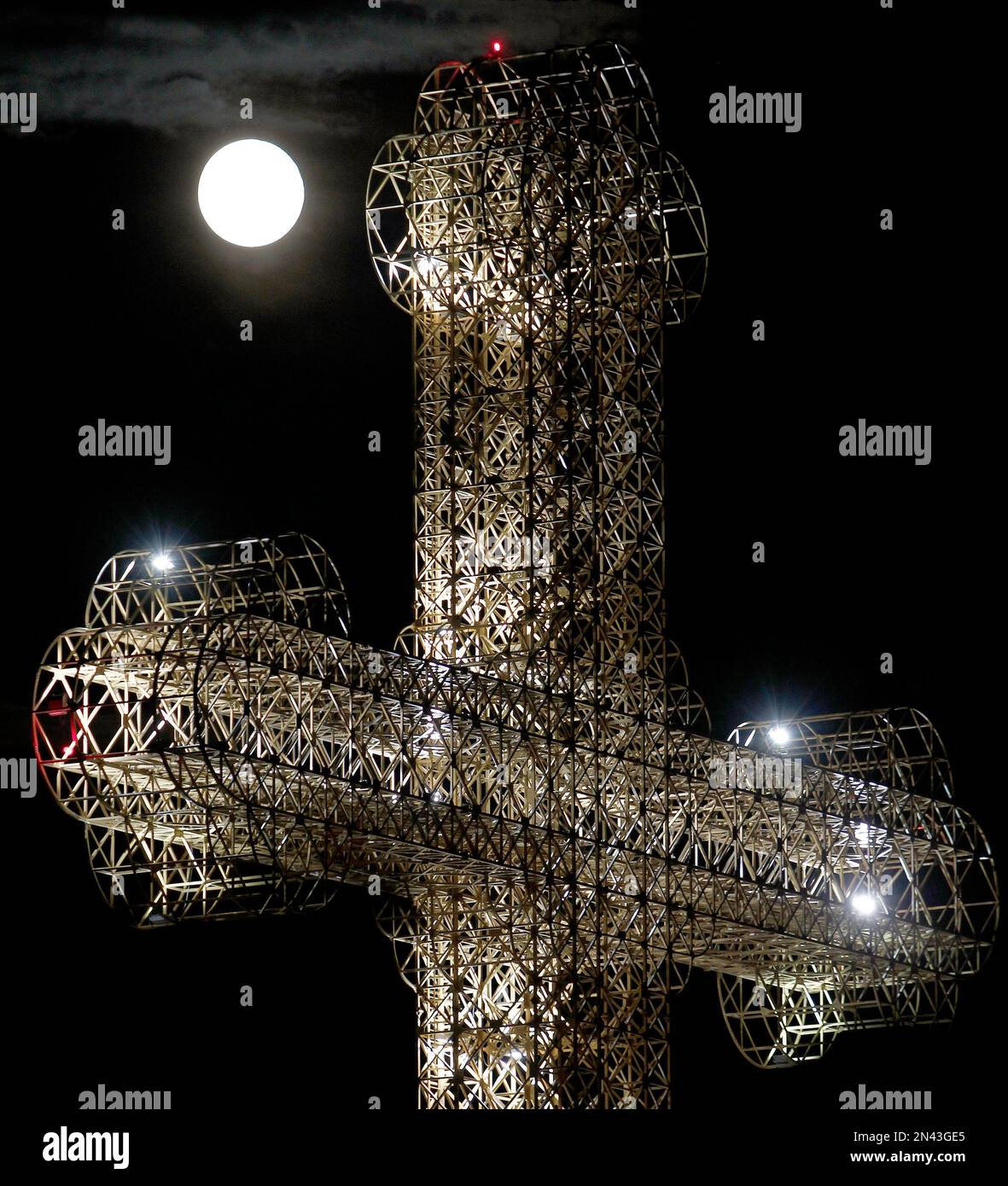 A perigee moon also known as a supermoon rises above the steel structure of a 51 meter (167 feet) tall cross in Skopje, Macedonia, Tuesday, Sept. 9, 2014. The phenomenon, which scientists call a "perigee moon," occurs when the moon in its elliptical orbit is relatively close to Earth and seen from the Earth near the horizon, appears larger and brighter than other full moons. This will be the third and final supermoon in 2014. (AP Photo/Boris Grdanoski) Banque D'Images