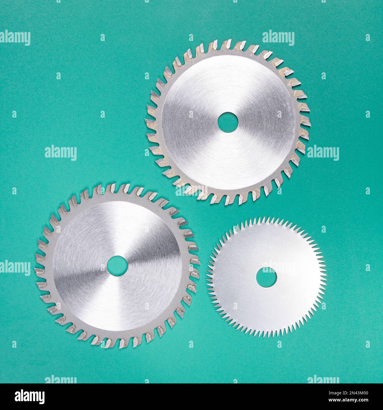 Jeu de trois disques à dents en carbure pour une scie à table sur fond vert. Banque D'Images