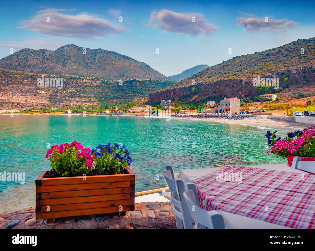 Magnifique paysage urbain d'été du village de Neo Itilo. Café hospitalier sur le rivage de la mer Ionienne avec un pot de fleurs en fleurs. Scène matinale ensoleillée de Pelo Banque D'Images