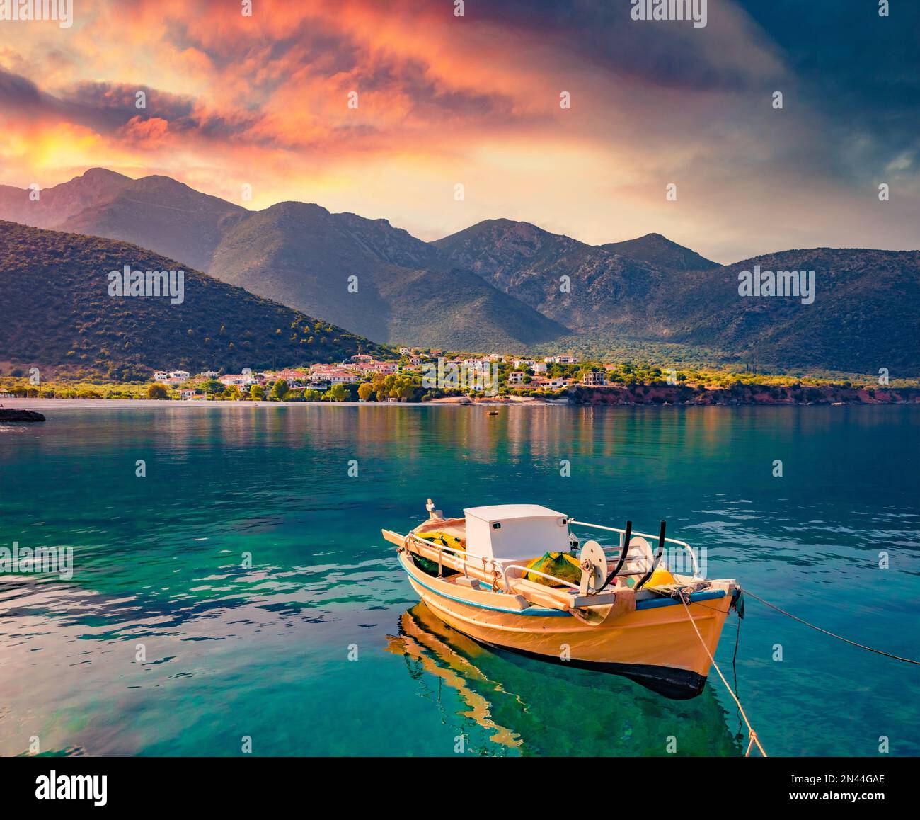 Lever de soleil coloré dans le port de Logari avec petit bateau de pêche avec village de Kyparissi en arrière-plan. Pittoresque scène estivale de la péninsule du Péloponnèse, Greec Banque D'Images