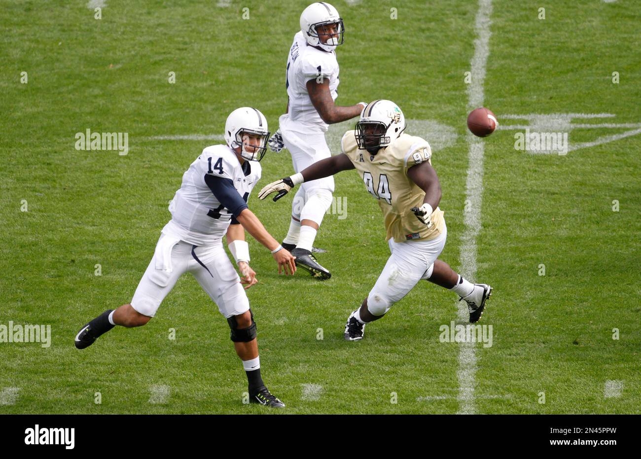 Penn State Nittany Lions Christian Hackenberg, left, throws the ball as UCF Knights Justin Tukes, right, closes in during the Croke Park Classic College Football match in Dublin, Ireland, Saturday, Aug. 30,2014. University of Central Florida hosted Penn State in their 2014 football Season Opener Saturday. This big season opener for UCF and Penn State is the first time that they have played outside the United States. (AP Photo/Peter Morrison) Banque D'Images