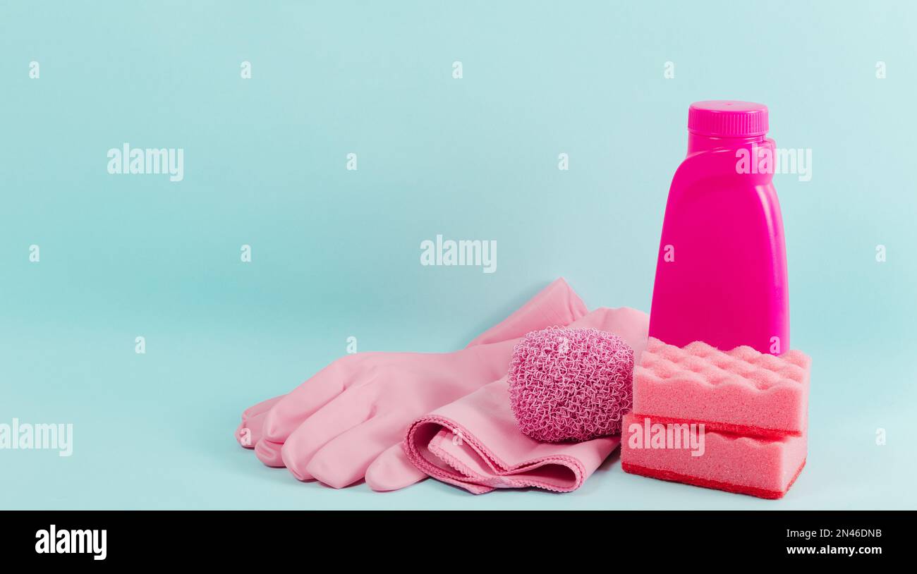 Nettoyage de la collection de fournitures roses sur fond bleu. Concept de travaux ménagers. Agent nettoyant, débarbouillettes, gants en caoutchouc, serviette et tampon à récurer Banque D'Images
