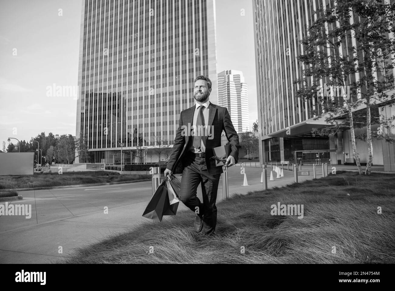 un homme heureux en tenue de cérémonie avec des sacs de shopping et de  boîte de cadeau à l'extérieur du bureau, anniversaire Photo Stock - Alamy