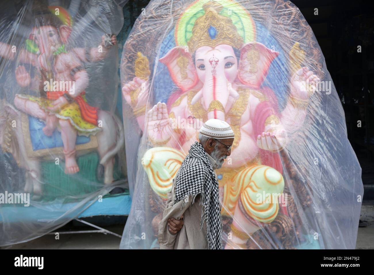 An Indian Muslim man walks past idols of elephant-headed Hindu God Ganesha displayed for sale ahead of the Ganesh Chaturthi festival in Hyderabad, India, Sunday, Aug.24, 2014. The festival is celebrated as the birthday of Lord Ganesha who is widely worshiped by Hindus as the god of wisdom, prosperity and good fortune. (AP Photo/Mahesh Kumar A.) Banque D'Images