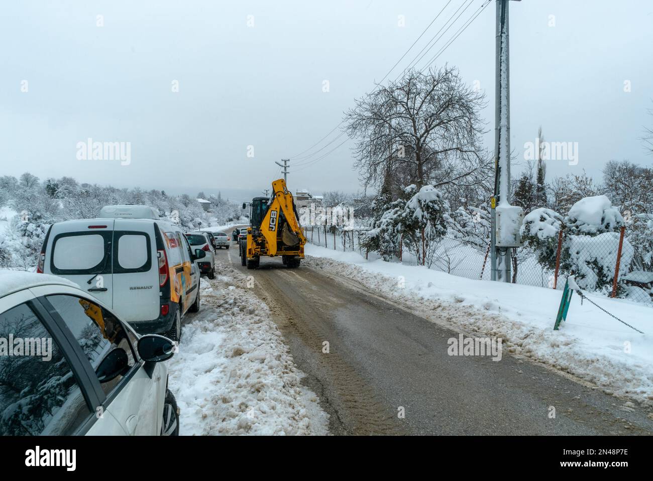 digger et voitures sur la route. Banque D'Images