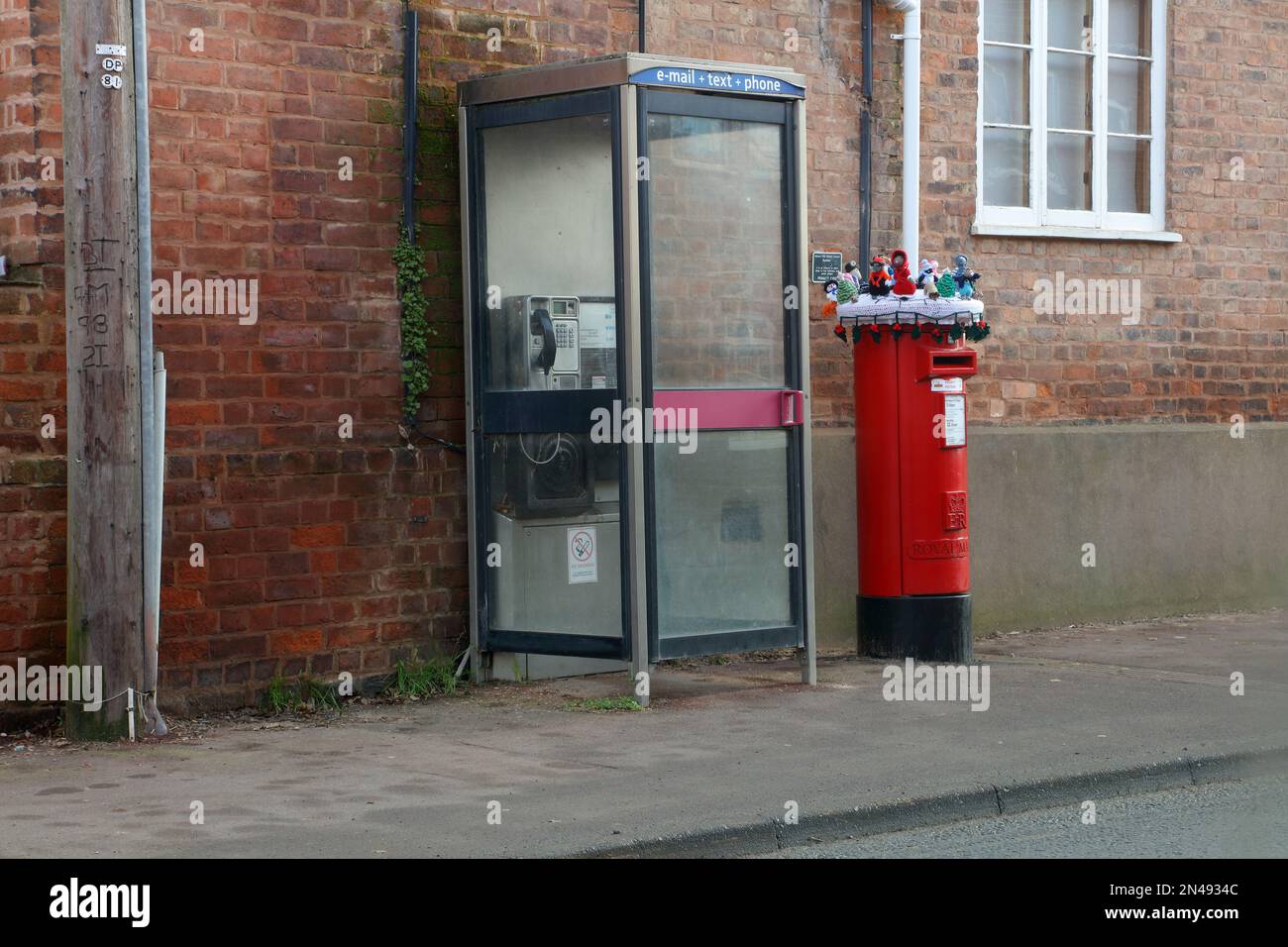 Un ensemble assez étrange de jouets tricotés au-dessus d'une boîte de pilier adjacente à une boîte de téléphone publique sur Old Street Upton upon Severn. Banque D'Images