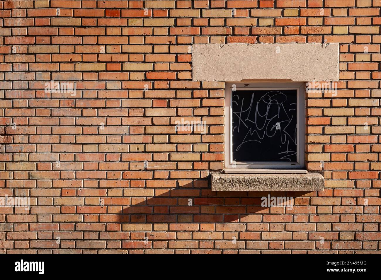 Une petite fenêtre avec inscription sur un mur de briques. Banque D'Images