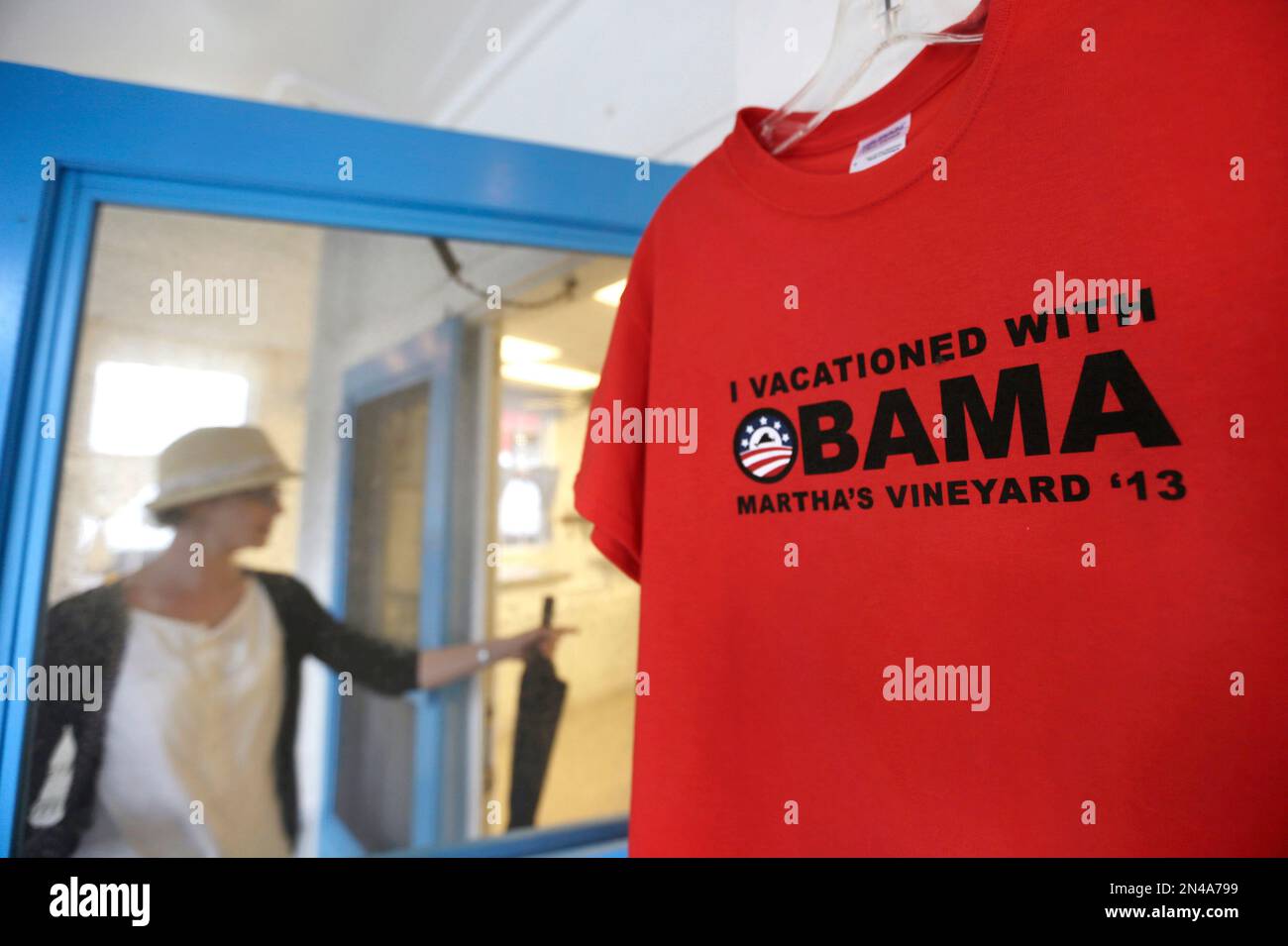 FILE - In this Aug. 9, 2013 file photo, a woman enters a fudge shop through a screen door, left, past a shirt bearing the name of President Barack Obama, in Oak Bluffs, Mass., on the island of Martha's Vineyard. President Obama and his family are returning to the island off the Massachusetts mainland Saturday, Aug. 9, 2014, for the longest summer vacation of his six-year presidency. (AP Photo/Steven Senne, File) Banque D'Images