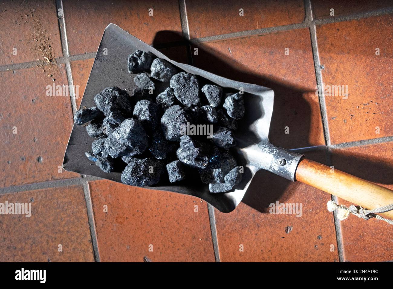 Petite pelle pleine de charbon sur un plancher de tuile rouge prêt à charger dans un poêle à charbon domestique pour le combustible domestique au pays de Galles Royaume-Uni Grande-Bretagne KATHY DEWITT Banque D'Images