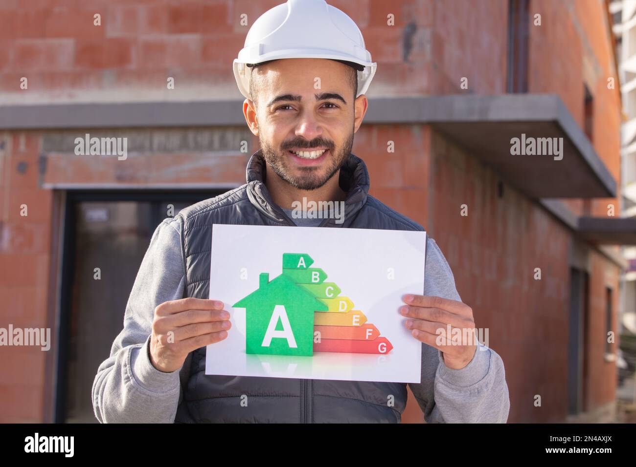 un constructeur heureux avec un panneau d'évaluation énergétique Banque D'Images