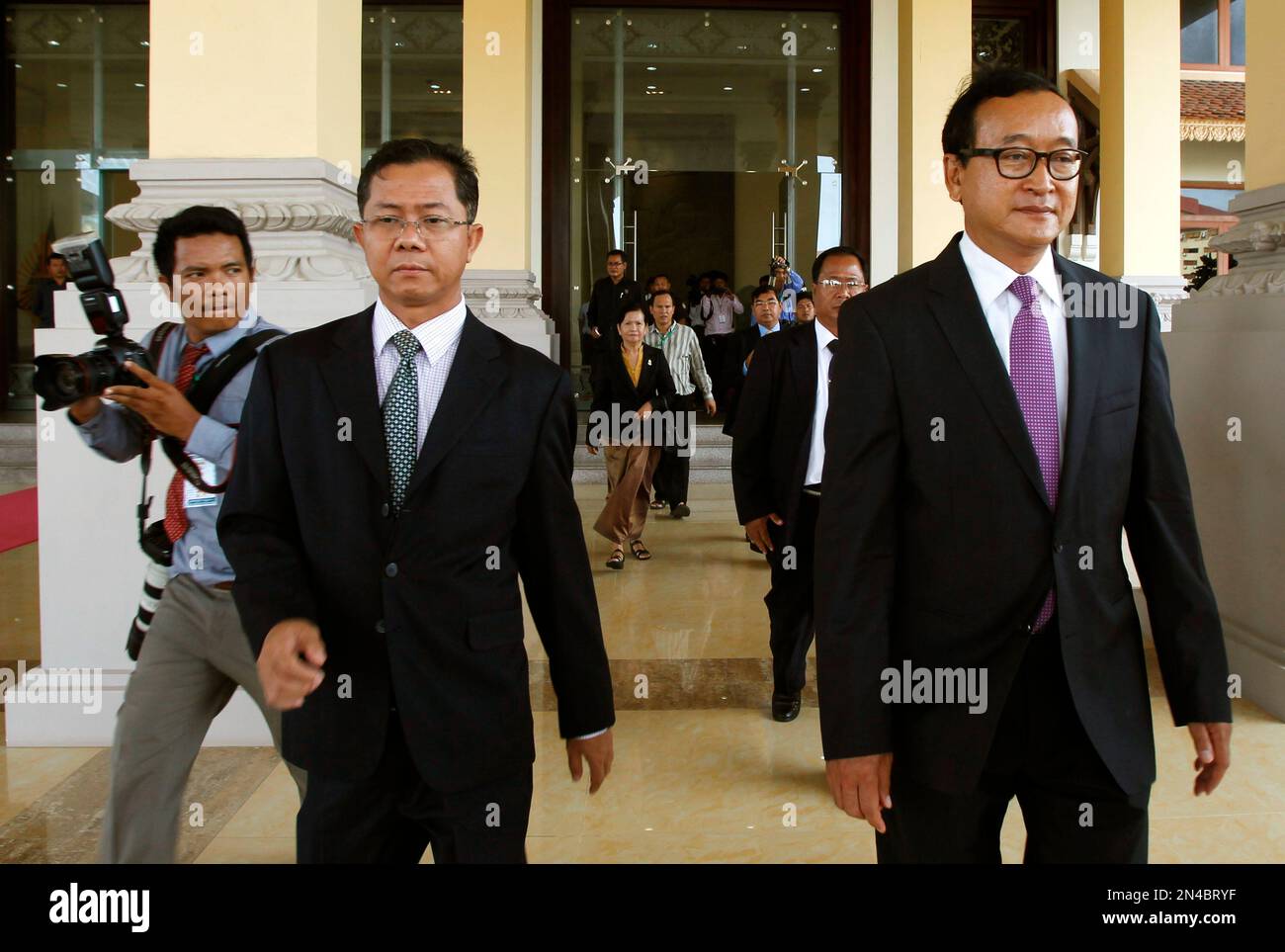 Cambodia's main opposition leader Sam Rainsy, right, of the Cambodia National Rescue Party, walks at the main entrance of the National Assembly after an immunity ceremony was announced, in Phnom Penh, Cambodia, Monday, July 28, 2014. Cambodia's National Assembly on Monday held an extraordinary session to ratify Sam Rainsy’s eligibility to assume membership. (AP Photo/Heng Sinith) Banque D'Images