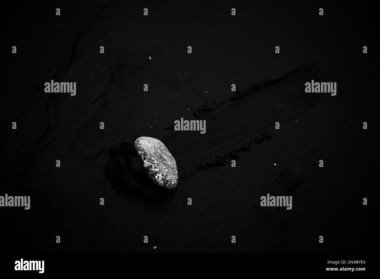 Vue de dessus en niveaux de gris d'une pierre sur du sable. Banque D'Images