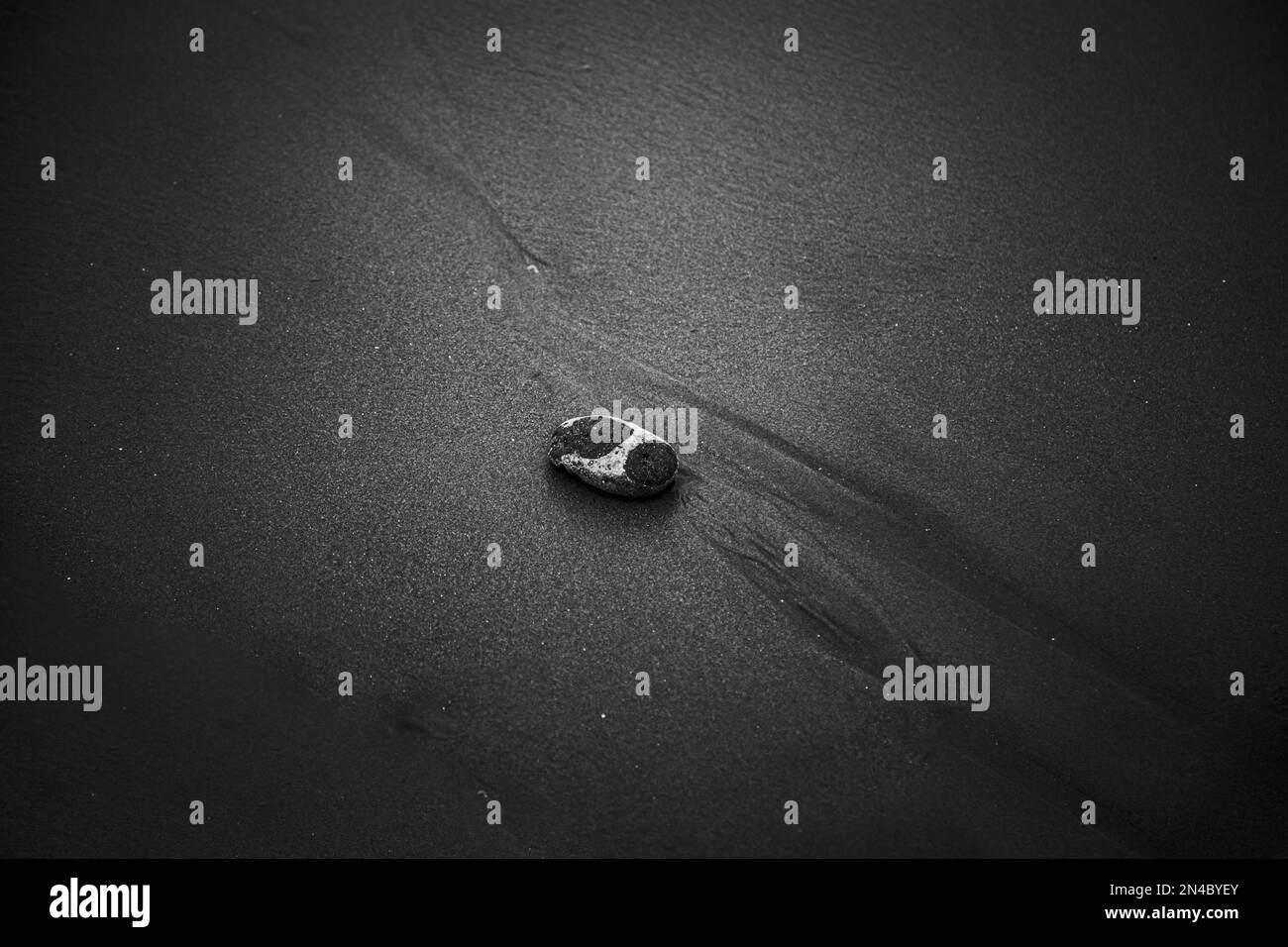 Vue de dessus en niveaux de gris d'une pierre sur du sable. Banque D'Images