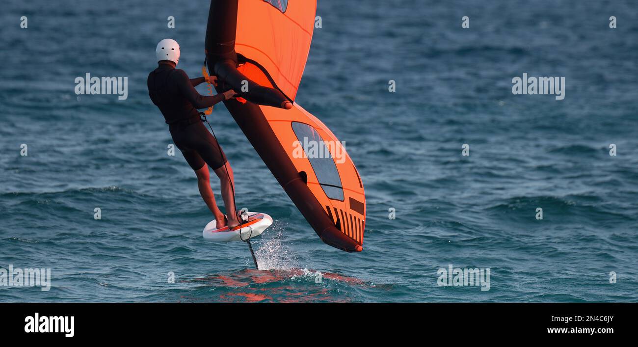 Un homme est l'aile de déjouer à l'aide d'ailes gonflables portatifs et de planches de surf hydrofoil dans un océan bleu, pilote sur une aile de vent, surf les vagues Banque D'Images