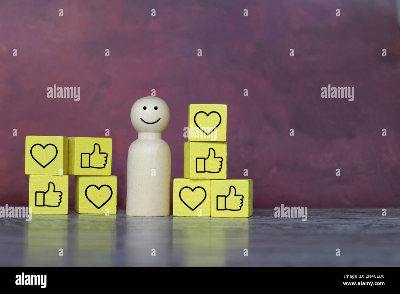 Poupée en bois souriante avec cœur et icône de pouce vers le haut. Copier l'espace pour le texte. Feedback positif, concept de validation sociale. Banque D'Images