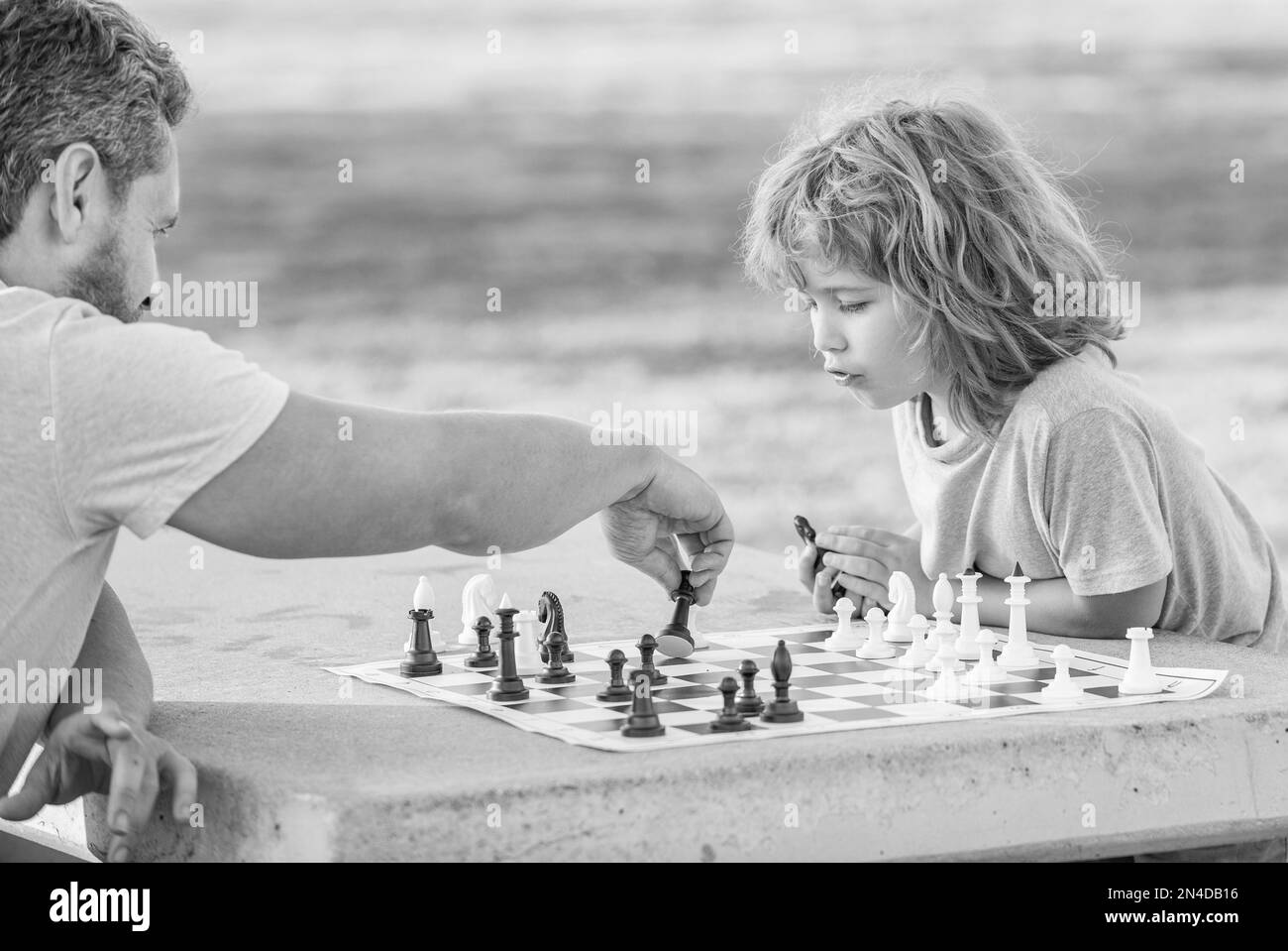 bonne famille de papa et fils enfant jouant aux échecs sur table dans le parc extérieur, tournoi d'échecs Banque D'Images