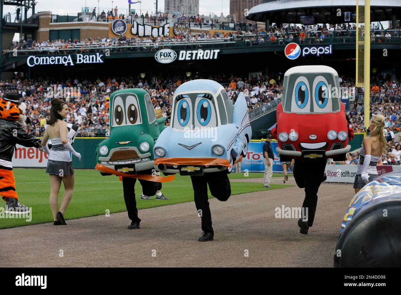 The Motor City Wheels mascot race with "Petey Pickup" (1954 Chevy pickup truck), "Bella Air" (1957 Bel Air), center, and "Corey Vette" (1958 Corvette) compete during the third inning of a baseball game between the Detroit Tigers and the Cleveland Indians in Detroit, Friday, July 18, 2014. (AP Photo/Carlos Osorio) Banque D'Images