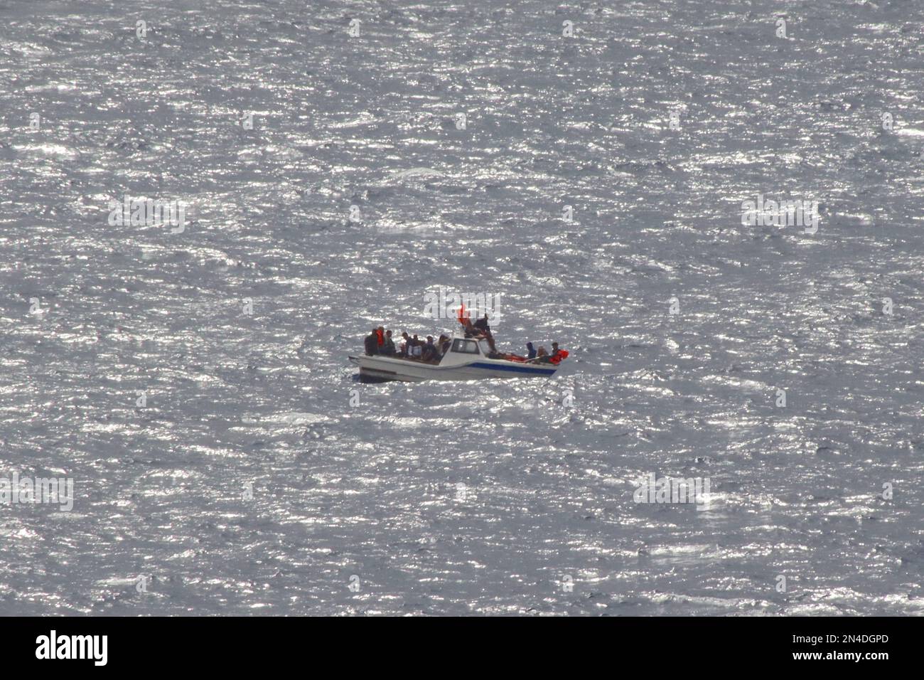 Les migrants algériens de sexe masculin brandirent des gilets de sauvetage pour attirer l'attention, ayant perdu de l'énergie sur leur bateau alors qu'il dévie dans la mer Méditerranée, août 2022. Banque D'Images