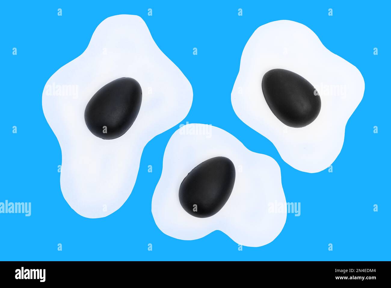 Mise en page créative composée d'œufs brouillés et d'œufs de Pâques peints en noir sur fond bleu. Fond bleu minimal. Vacances de printemps conc Banque D'Images
