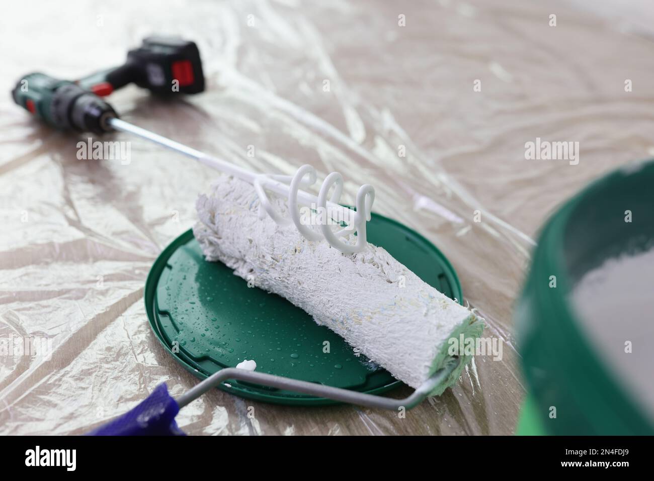 Mélangeur de peinture, brosse rotative et seau avec peinture blanche sur plancher couvert. Banque D'Images
