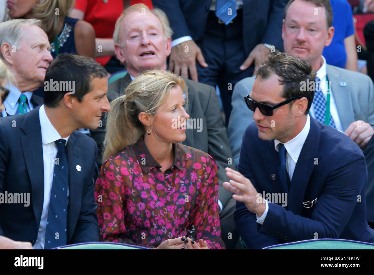 British actor Jude Law, right, talks with Bear and Shara Grylls, center, as former golfer Jack Nicklaus, rear left, and former tennis player Rod Laver, rear center, sit in the row behind in the Royal Box on centre court prior to the men's singles semifinal match between Novak Djokovic of Serbia and Grigor Dimitrov of Bulgaria at the All England Lawn Tennis Championships in Wimbledon, London, Friday July 4, 2014. (AP Photo/Pavel Golovkin) Banque D'Images