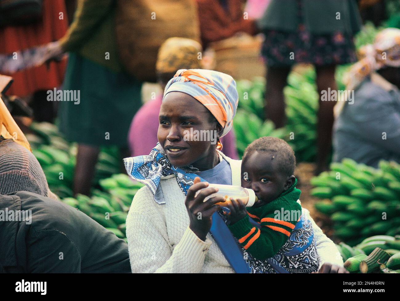 Kenya. Mère allaitant l'enfant du biberon sur le marché. Banque D'Images