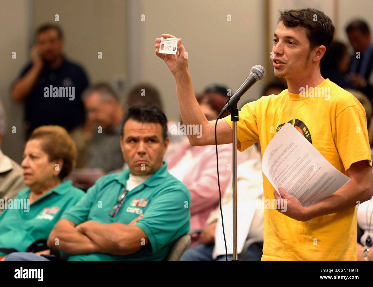 Pomona Economic Opportunity Center organizer Benjamin Wood, right, displays his organization's workers identification card during a California Department of Motor Vehicles hearing in downtown Los Angeles on Tuesday, June 24, 2014 to take public comments on proposed rules by which immigrants in the country illegally may obtain driver's licenses. The state expects 1.4 million people to apply in the first three years. (AP Photo/Damian Dovarganes) Banque D'Images