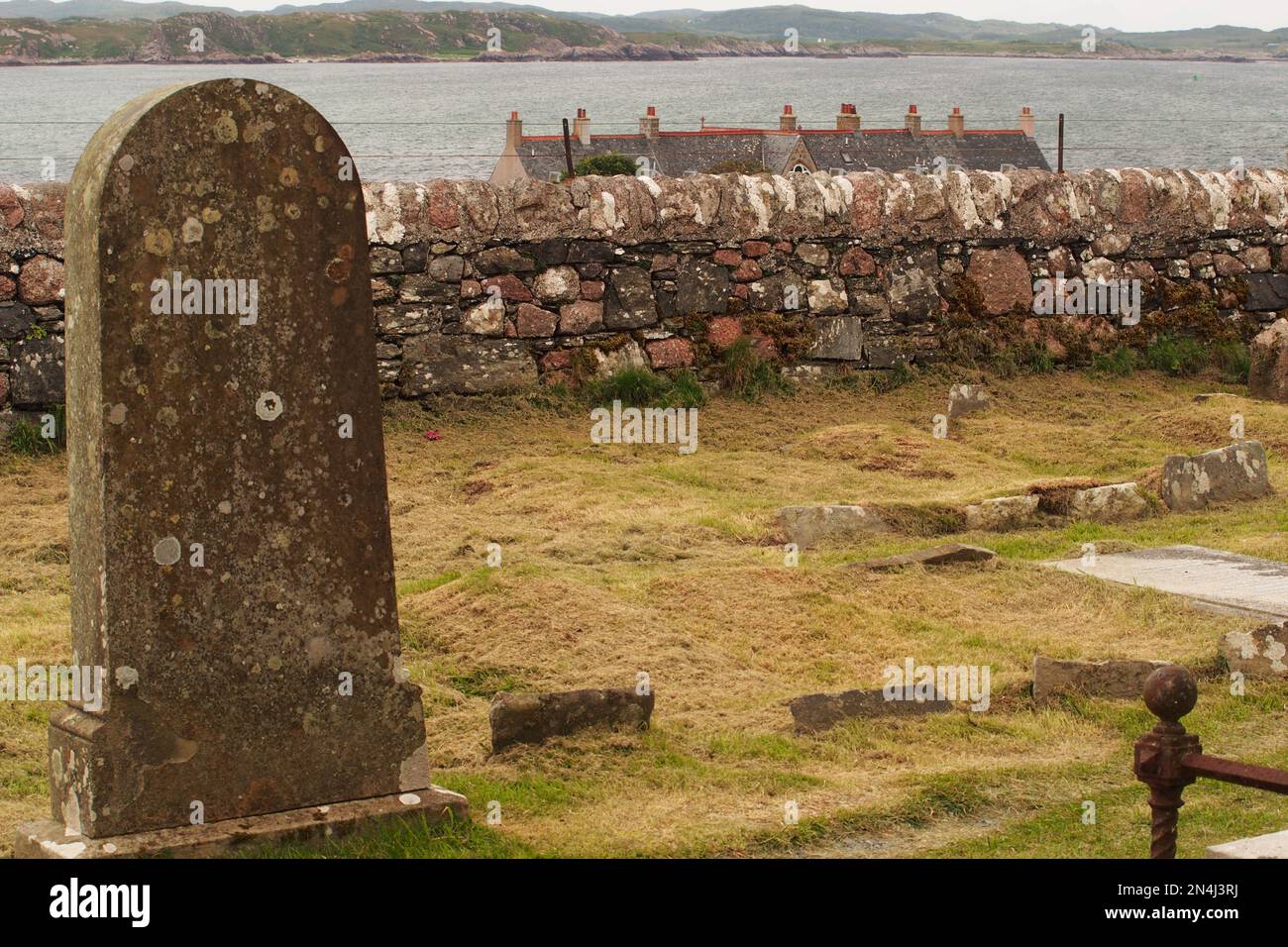Les toits de la rangée historique de maisons mitoyennes, donnant sur le son d'Iona, avec le cimetière et la pierre tombale en premier plan Banque D'Images