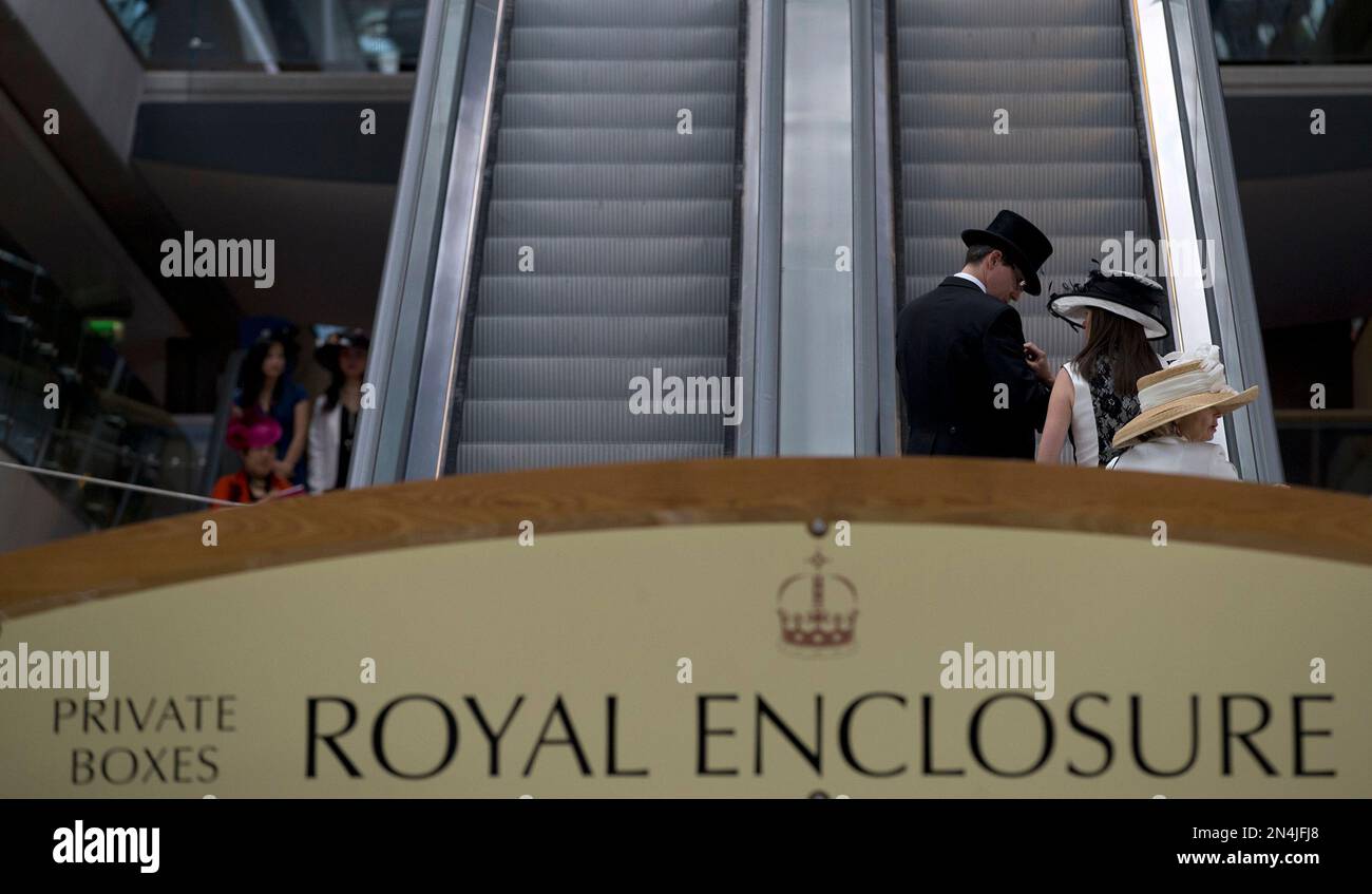 Racegoers take the escalator to private boxes in the Royal Enclosure on the third day of the Royal Ascot horse racing meeting, which is traditionally known as Ladies Day, at Ascot, England, Thursday, June, 19, 2014. Royal Ascot the annual five day horse race meeting that Britain's Queen Elizabeth II attends every day of the event. (AP Photo/Alastair Grant) Banque D'Images