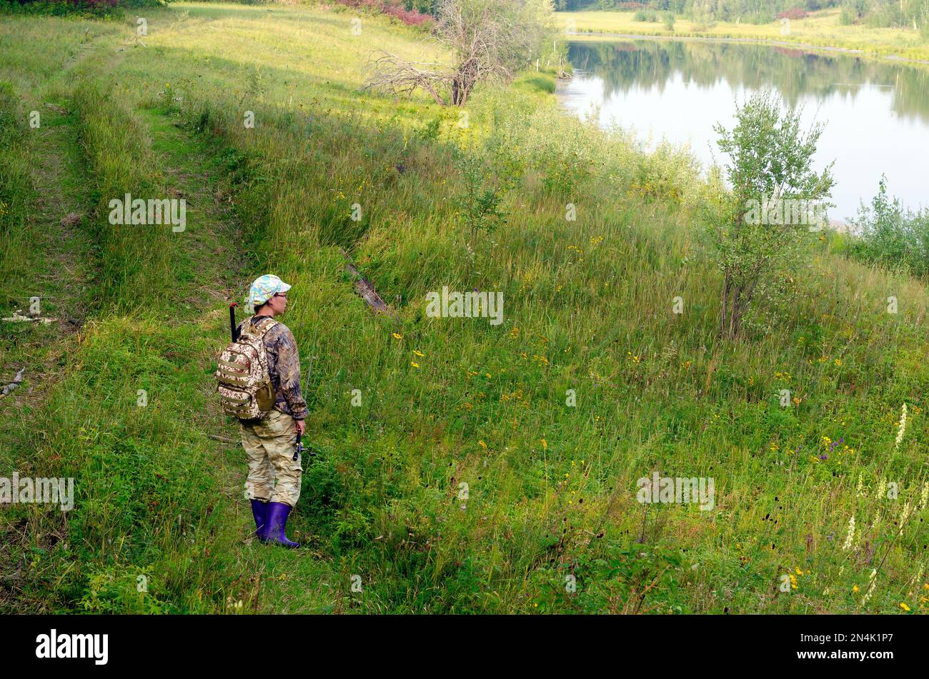 Yakut asiatique fille pêcheur touristique vêtu de vêtements de couleur protectrice avec un sac à dos et une canne à pêche dans sa main sur la piste à la sauvage l Banque D'Images