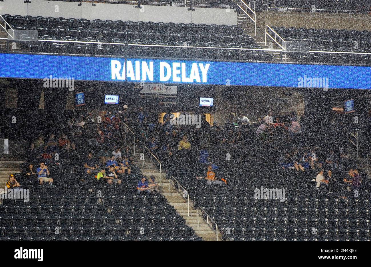 Mets fans seek shelter under the stands from the pouring rain during a ...