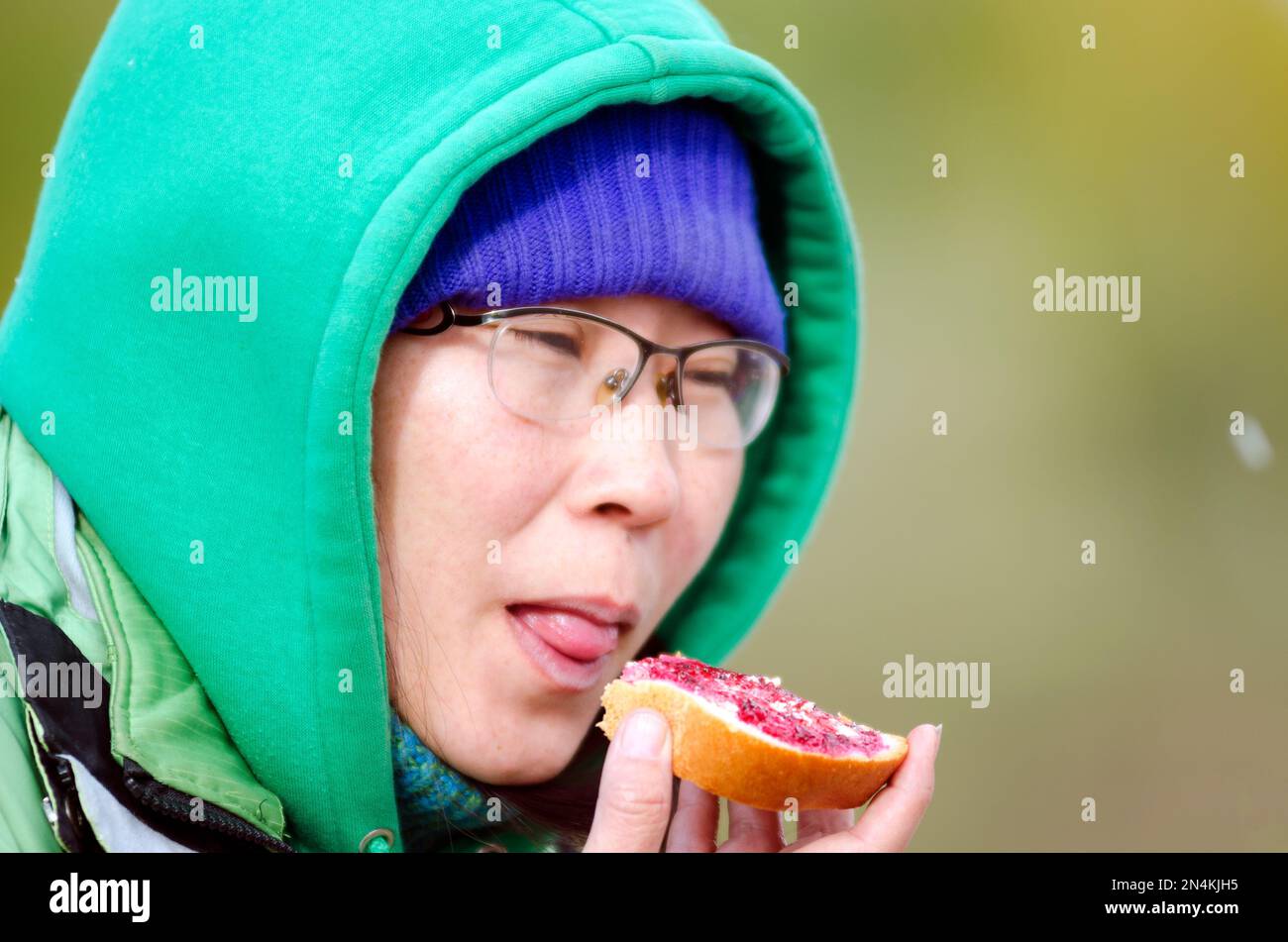 Yakut asiatique fille mangeant du pain sandwich avec confiture fermant les yeux avec plaisir sur le fond des flocons de neige volants. Banque D'Images