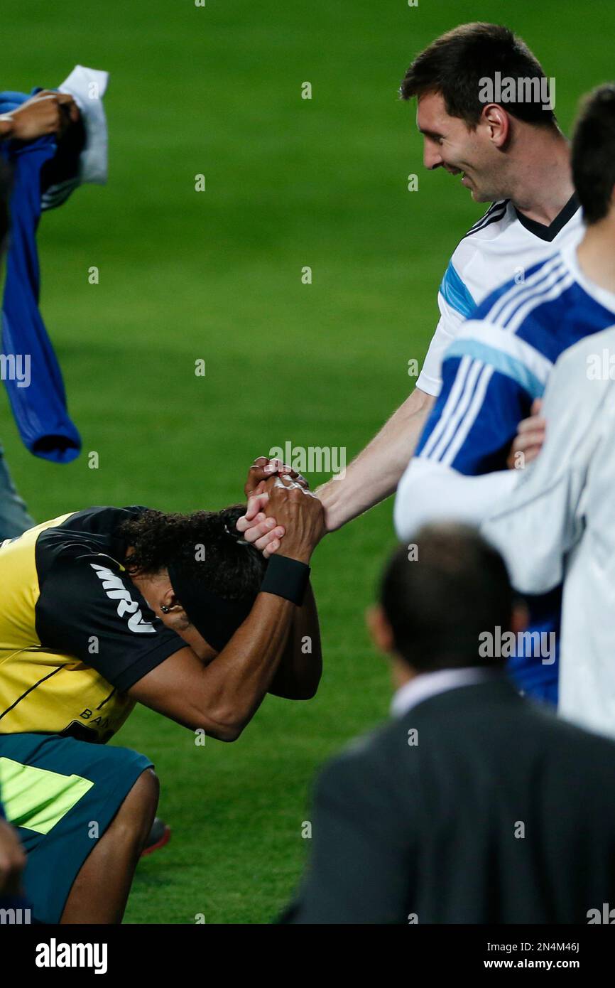 Argentina's Lionel Messi, right, shakes the hands of a fan who invaded the pitch and who resembles Brazilian soccer player Ronaldinho, left, at the end of a training session at Independencia Stadium in Belo Horizonte, Brazil, Wednesday, June 11, 2014. Argentina will play in group F of the Brazil 2014 soccer World Cup. (AP Photo/Bruno Magalhaes) Banque D'Images