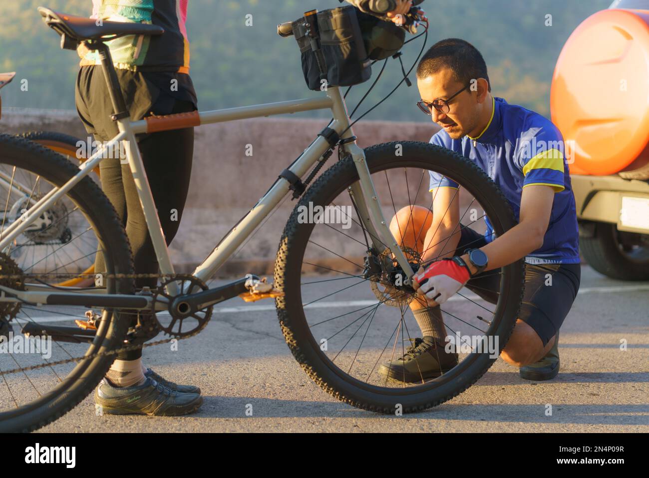 Un couple cycliste asiatique assemble des vélos pour une promenade matinale en vélo au bord du lac. Banque D'Images