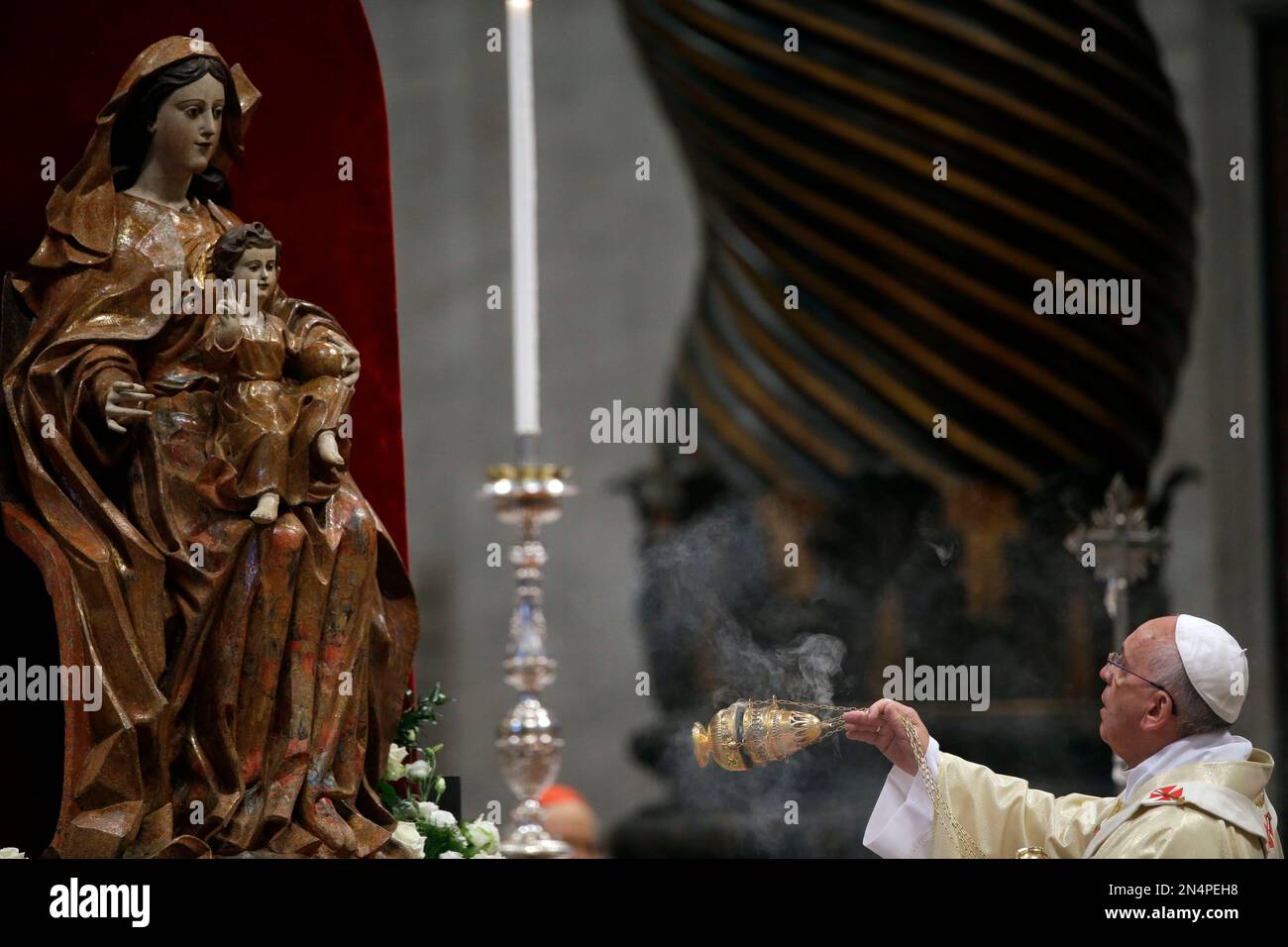 Pope Francis asperses incense in front of a statue of the Virgin Mary