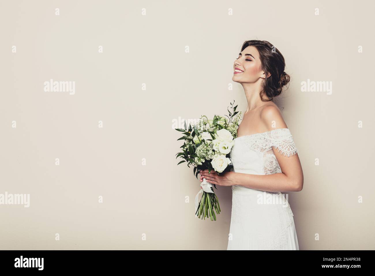 Jeune mariée portant une robe de mariage avec beau bouquet sur fond beige.  Espace pour le texte Photo Stock - Alamy