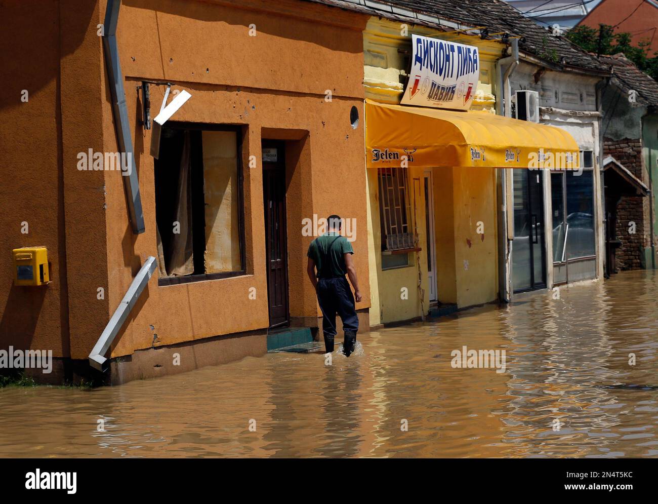 A man inspects a house in street where flood waters have withdrawn in Obrenovac, some 30 kilometers (18 miles) southwest of Belgrade, Serbia, Tuesday, May 20, 2014. Serbia, Bosnia and Croatia have been hit by the worst flooding in more than 100 years, forcing half a million people out of their homes and leading to more than three dozen deaths. (AP Photo/Darko Vojinovic) Banque D'Images