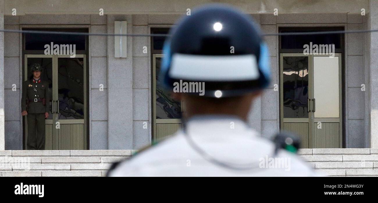 A North Korean soldier, left, looks at the south side as a South Korean soldier, center, stands guard at the border village of Panmunjom, which has separated the two Koreas since the Korean War, in Paju, north of Seoul, South Korea, Wednesday, May 14, 2014. North Korea threatened Tuesday to "wipe out" South Korea's government in a furious response a day after a Seoul official said the North "must disappear soon," in an escalation of rhetoric between the rivals. (AP Photo/Lee Jin-man) Banque D'Images