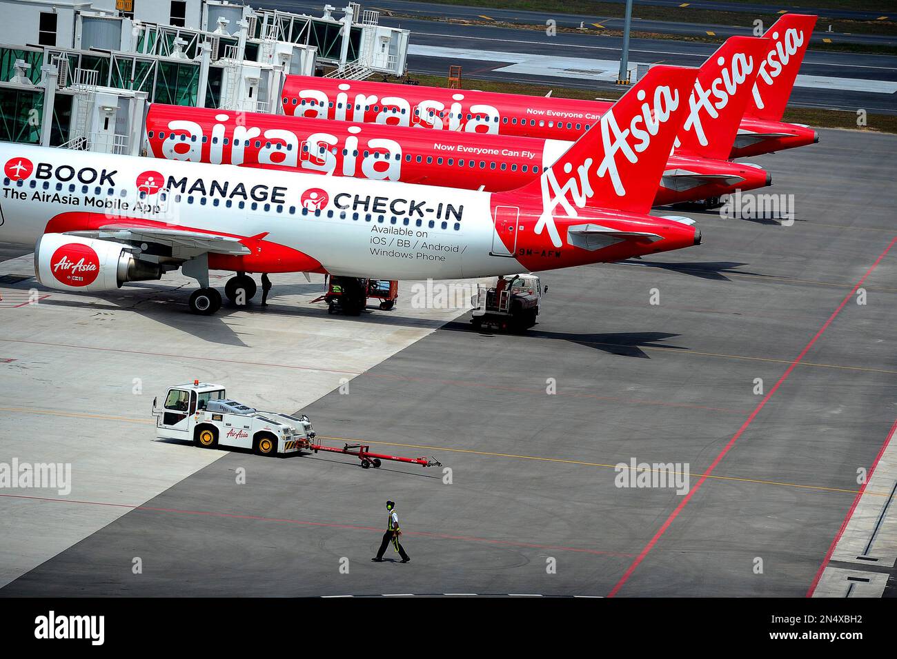 A ground crew man walks past a fleet of AirAsia's passenger jets on the tarmac of the new low cost terminal KLIA2 in Sepang, Malaysia, Friday, May 9, 2014. AirAsia on Friday began its full operations from KLIA2. (AP Photo/Joshua Paul) Banque D'Images