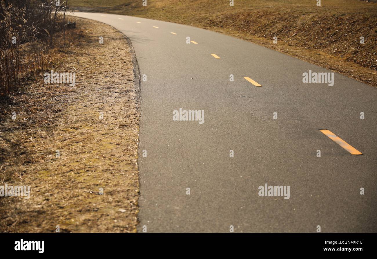 Piste cyclable au coucher du soleil sur une longue route Banque D'Images