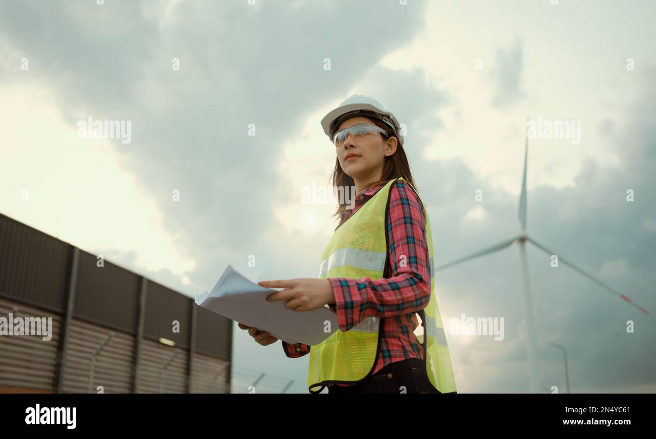 Femme asiatique ingénieur travaillant et tenant le rapport à la centrale éolienne. Banque D'Images