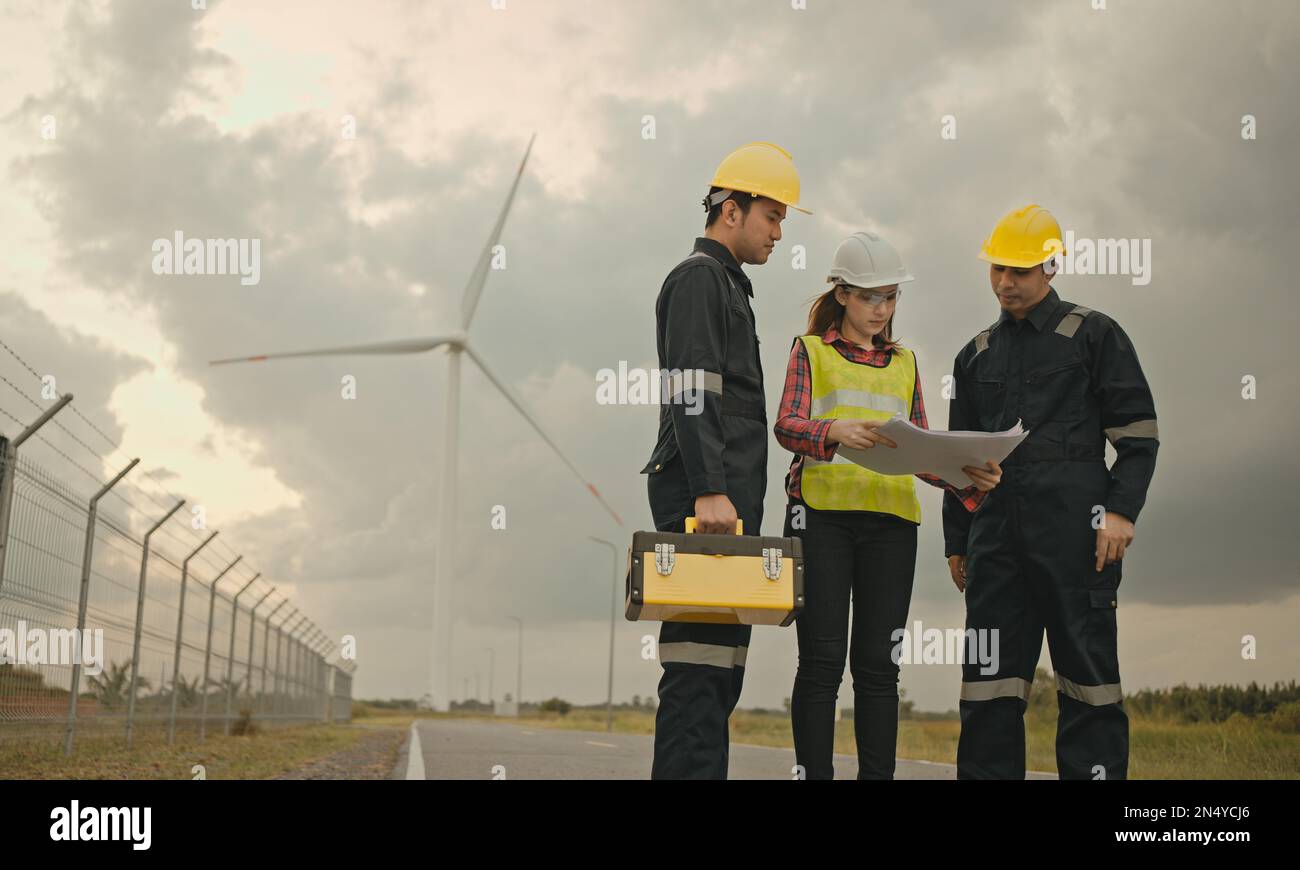 Trois techniciens sont ingénieurs en uniforme avec debout et vérification de la centrale électrique de la ferme éolienne. Énergie propre et environnement. Banque D'Images